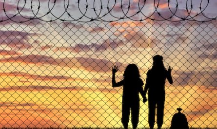 Silhouette von hungrigen Kindern hinter einem Stacheldrahtzaun bei Sonnenuntergang
