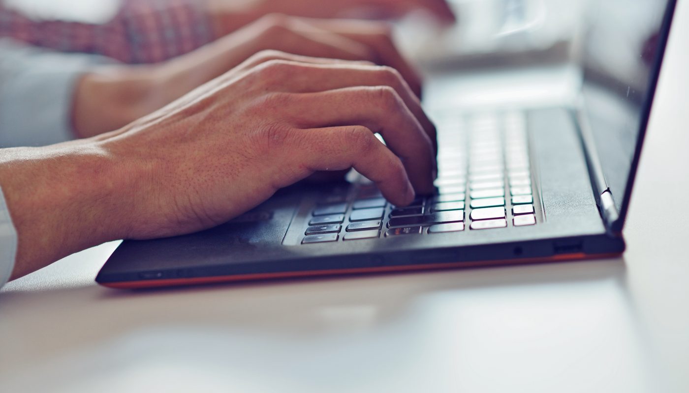 Hände schreiben auf einer Laptop Tastatur